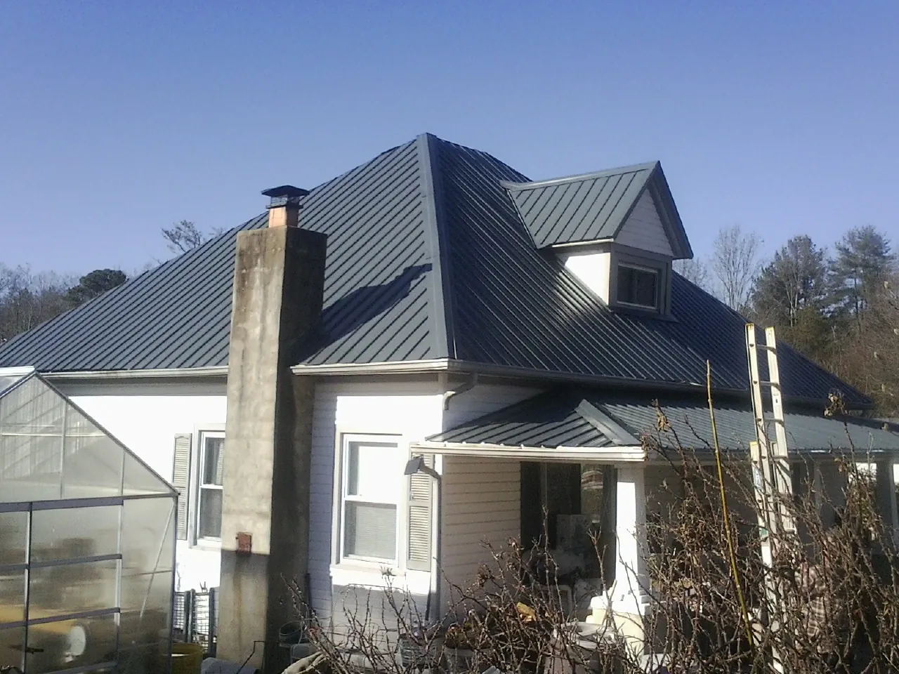 Dark blue standing seam metal roof on a white farmhouse with dormer — Slate & Tile Roof Repair by Roofing Brothers in Murrieta