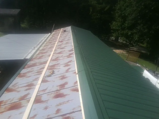 Old rusted panels beside newly installed green metal roofing — Wind Damage Roof Repair by Roofing Brothers in Murrieta
