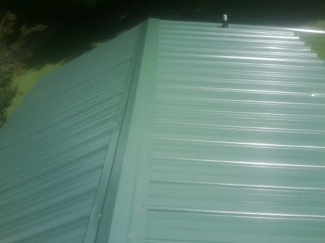 New green metal panels meeting at the ridge of a roof — Flat Roof Repair work by our crew in Murrieta