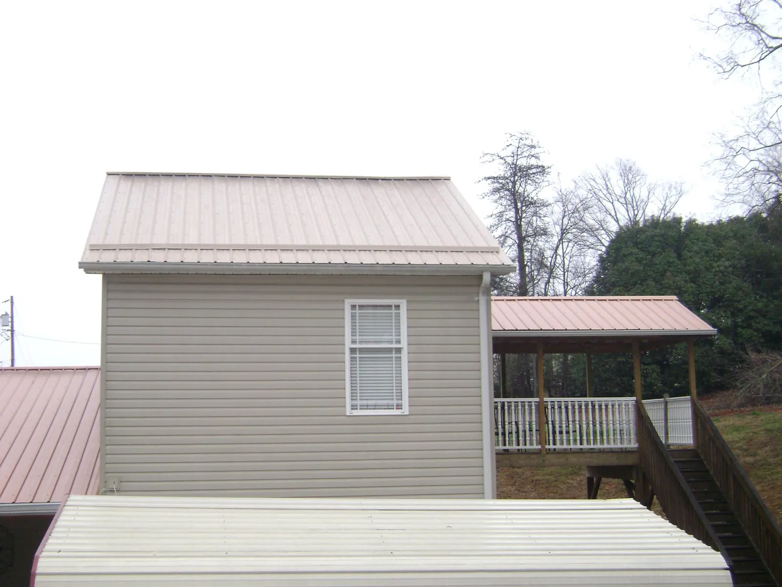 Tan metal roofs on a two story addition and attached porch, from a Roof Replacement job in Murrieta