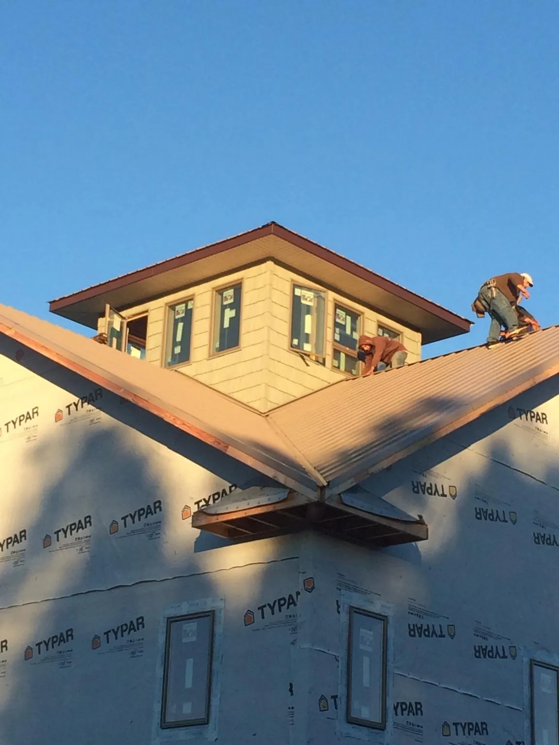 Roofers working around a rooftop cupola on a new metal roof at sunset — Roof Waterproofing in Murrieta by Roofing Brothers